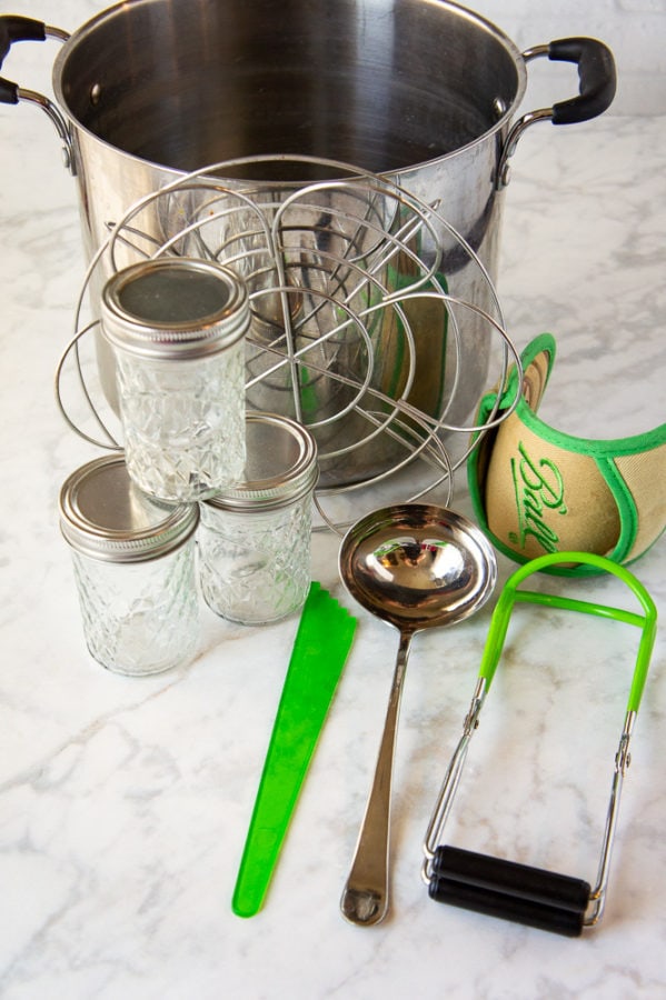 a pot with canning supplies arrange beside it