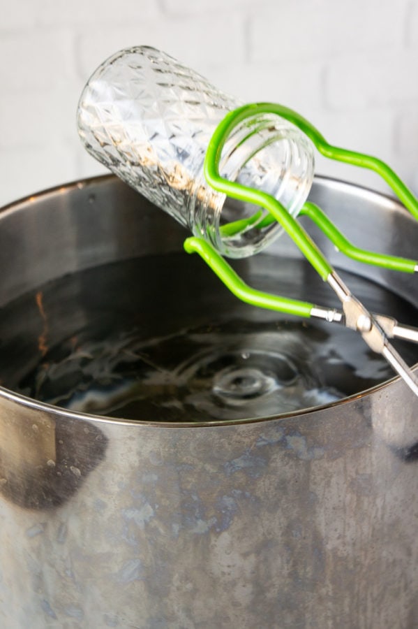 a jar being lifted from hot water with jar clamps