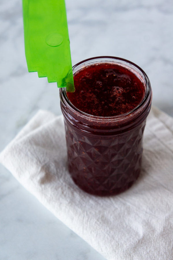 a ruler measuring 1/4 inch of headspace between the jar and top of the jam it's filled with