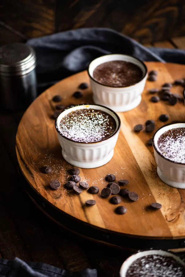 chocolate custard in ramekins on a wooden circle