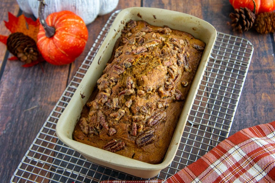 baked whole wheat pumpkin bread in a loaf pan on a cooling rack
