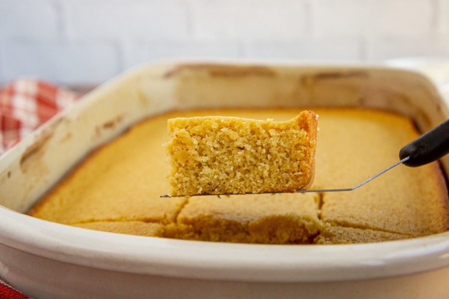 a slice of cornbread being lifted from a 9x13 pan