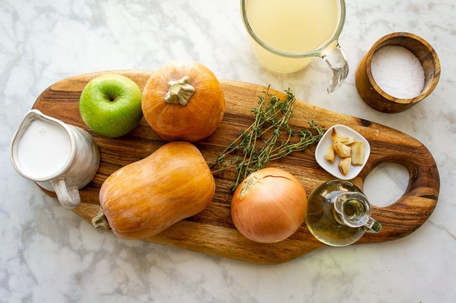 ingredients for making honeynut squash soup on a wooden cutting board