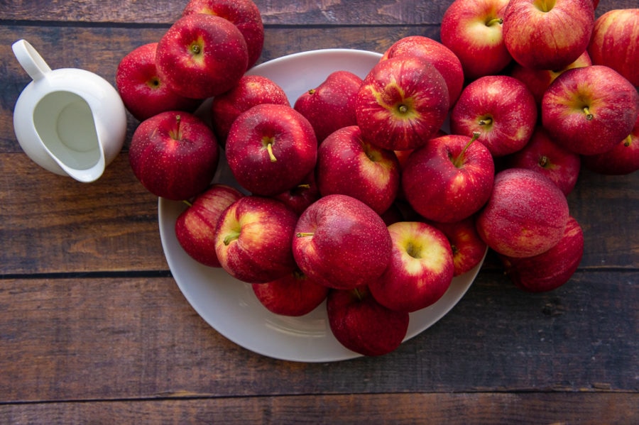 a pile of apples with a small carafe of water