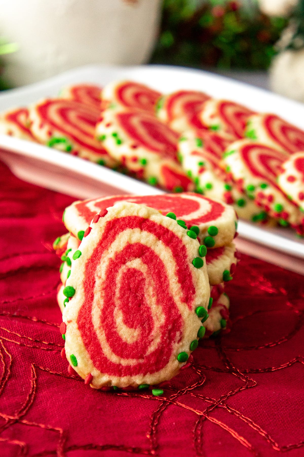 a Christmas themed pinwheel cookie in front of a stack of additional cookies.