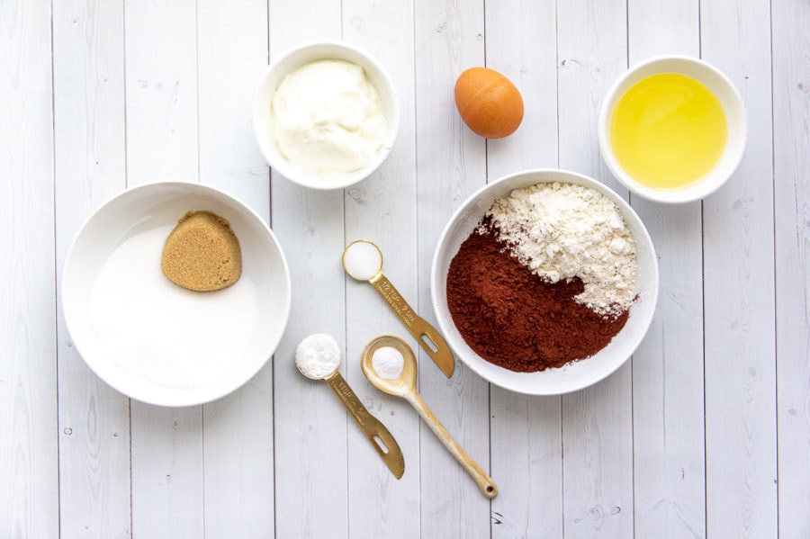 ingredients for baked chocolate donuts including sugar, egg, oil, flour, cocoa powder, and yogurt