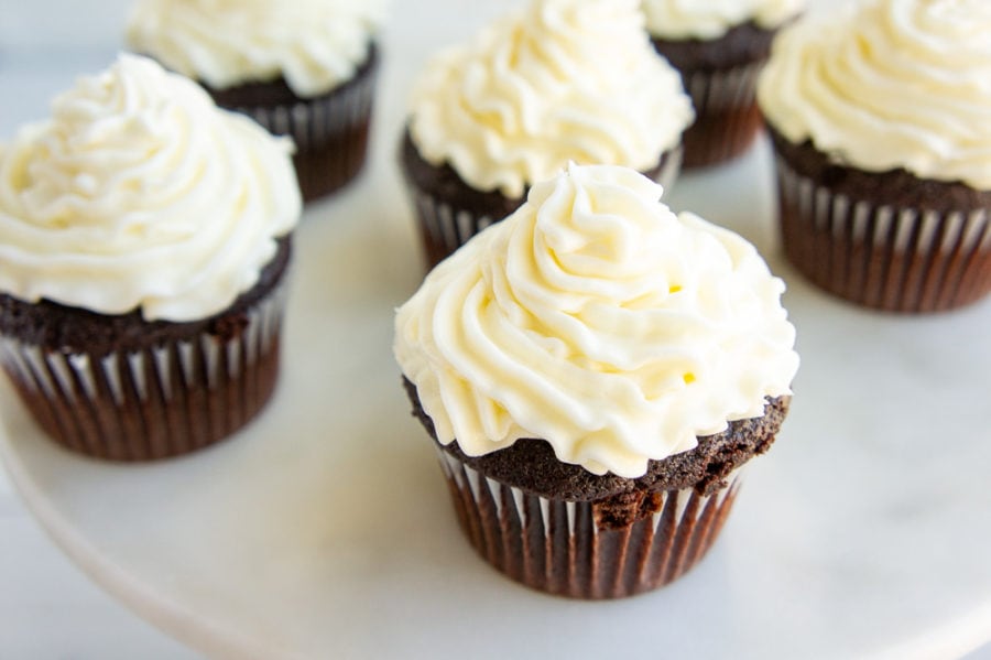 chocolate cupcakes with white frosting on a cake stand