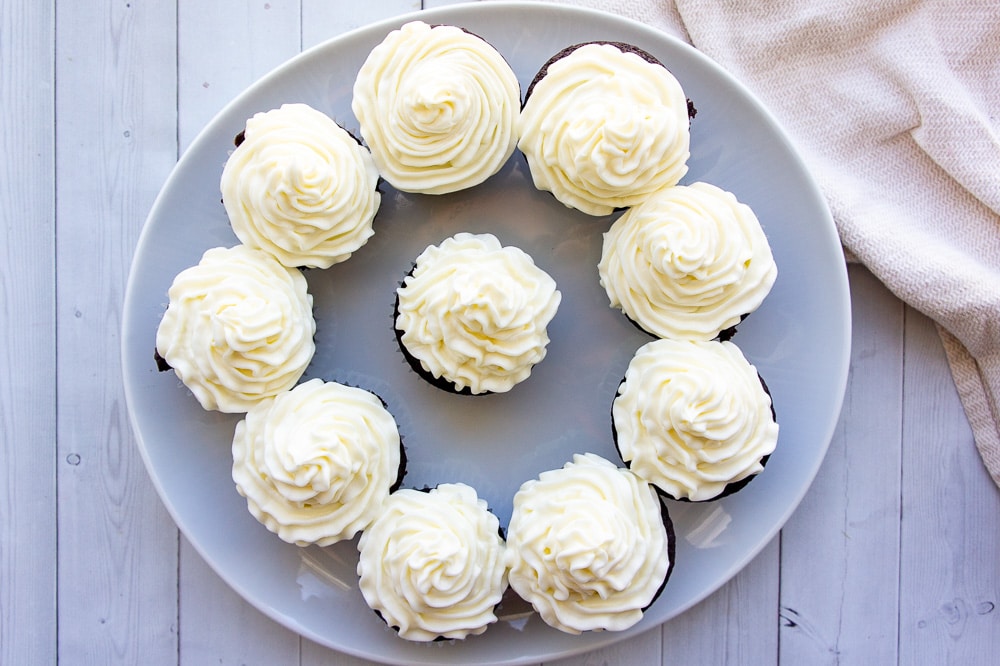 a plate of cupcakes decorated with a simple white vanilla frosting