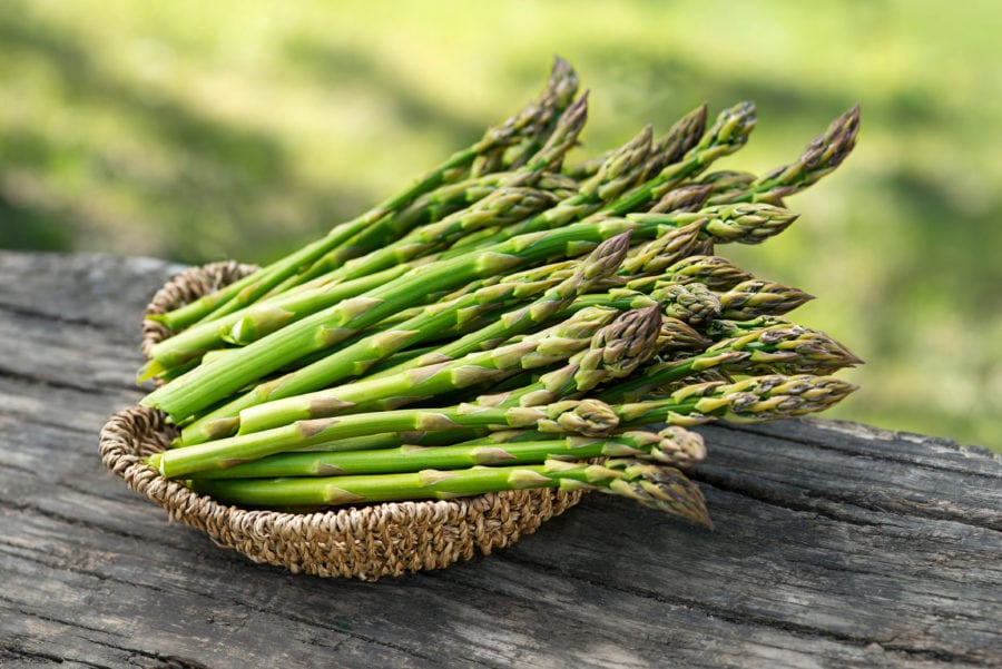 a basket of fresh asparagus on a wooden table