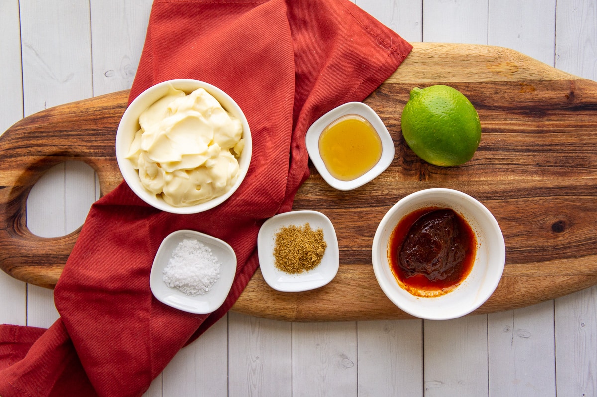 ingredients to make chipotle lime sauce including adobo peppers, mayo, lime, honey, and spices