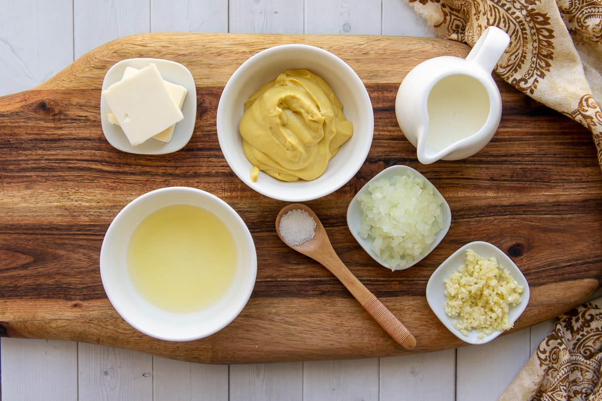 Ingredients to make dijon cream sauce including mustard, butter, cream, onions, and garlic