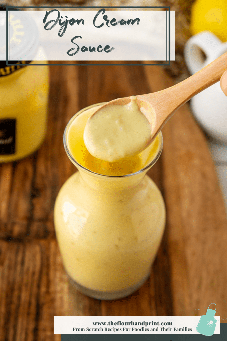 A spoon displaying creamy dijon mustard sauce in a glass jar