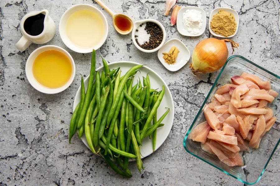 Ingredients to make stir fried chicken and green beans including soy sauce, mirin, rice wine vinegar, onion, garlic, and brown sugar