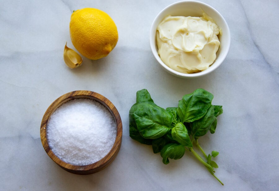ingredients to make flavored mayo including fresh basil, garlic, lemon, and salt.