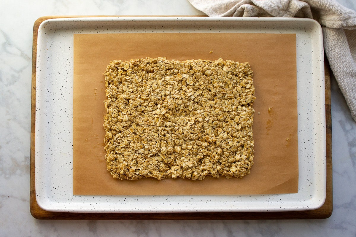 baking nut-free granola bars in a large rectangle on parchment paper.