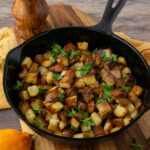 a cast iron pan full of potatoes with parsley sprinkled on top.