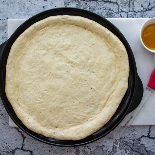 a pan with pizza dough pressed out on it.