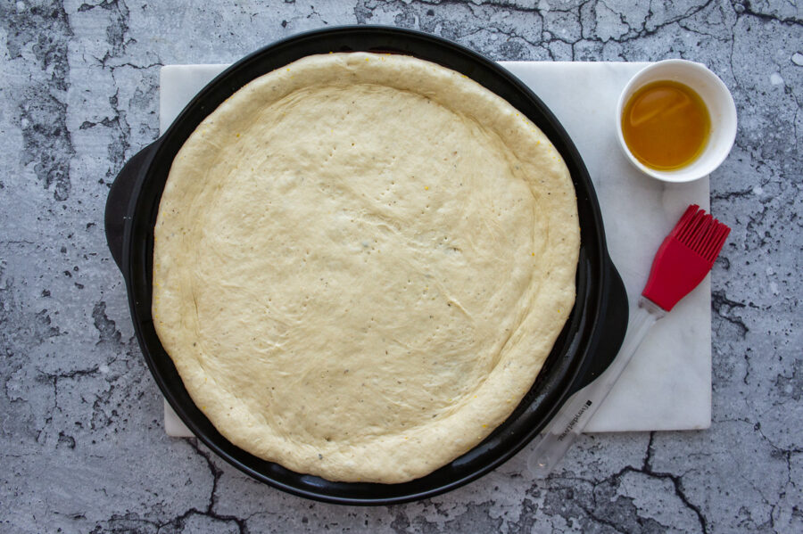 a pan with pizza dough pressed out on it.