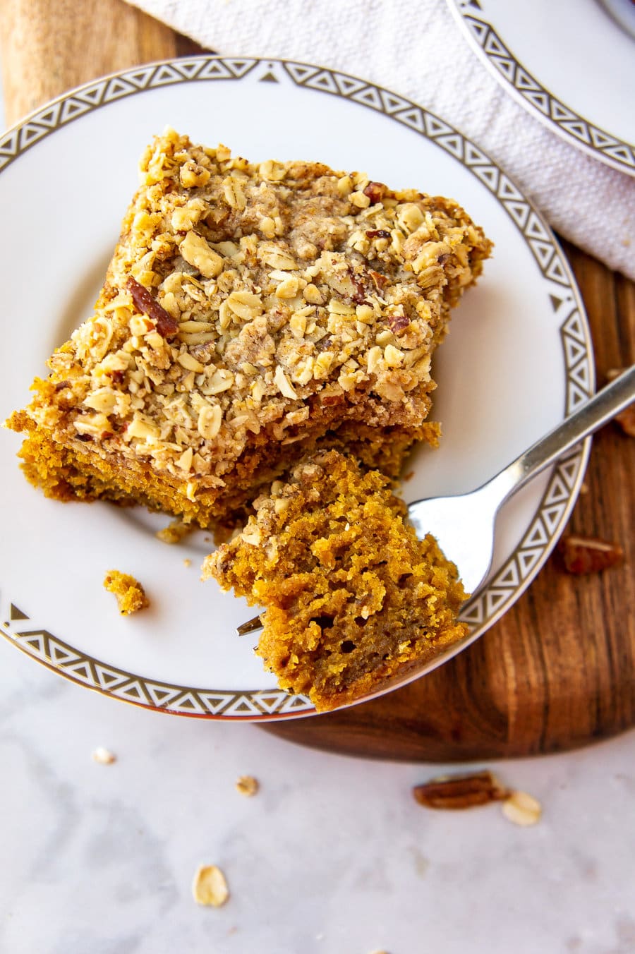 a slice of pumpkin cake with a pecan streusel topping with one bite cut off on a fork.