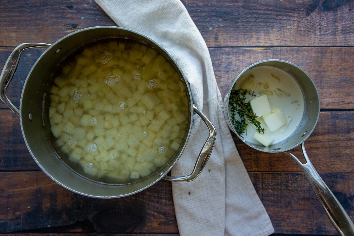 a pot of boiled potatoes and a pot of cream and butter with thyme and garlic.
