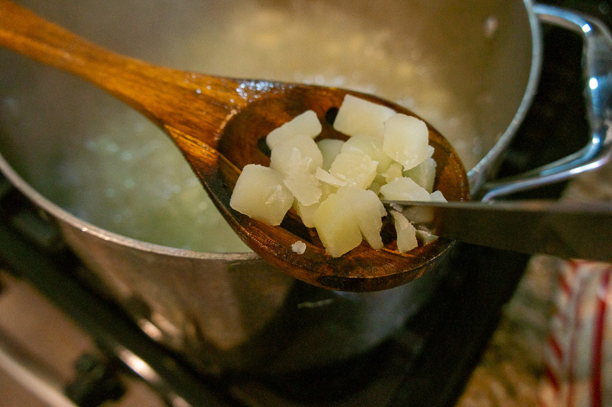 a knife cutting into a very tender boiled potato.