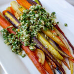 a platter of roasted glazed rainbow carrots topped with gremolata.