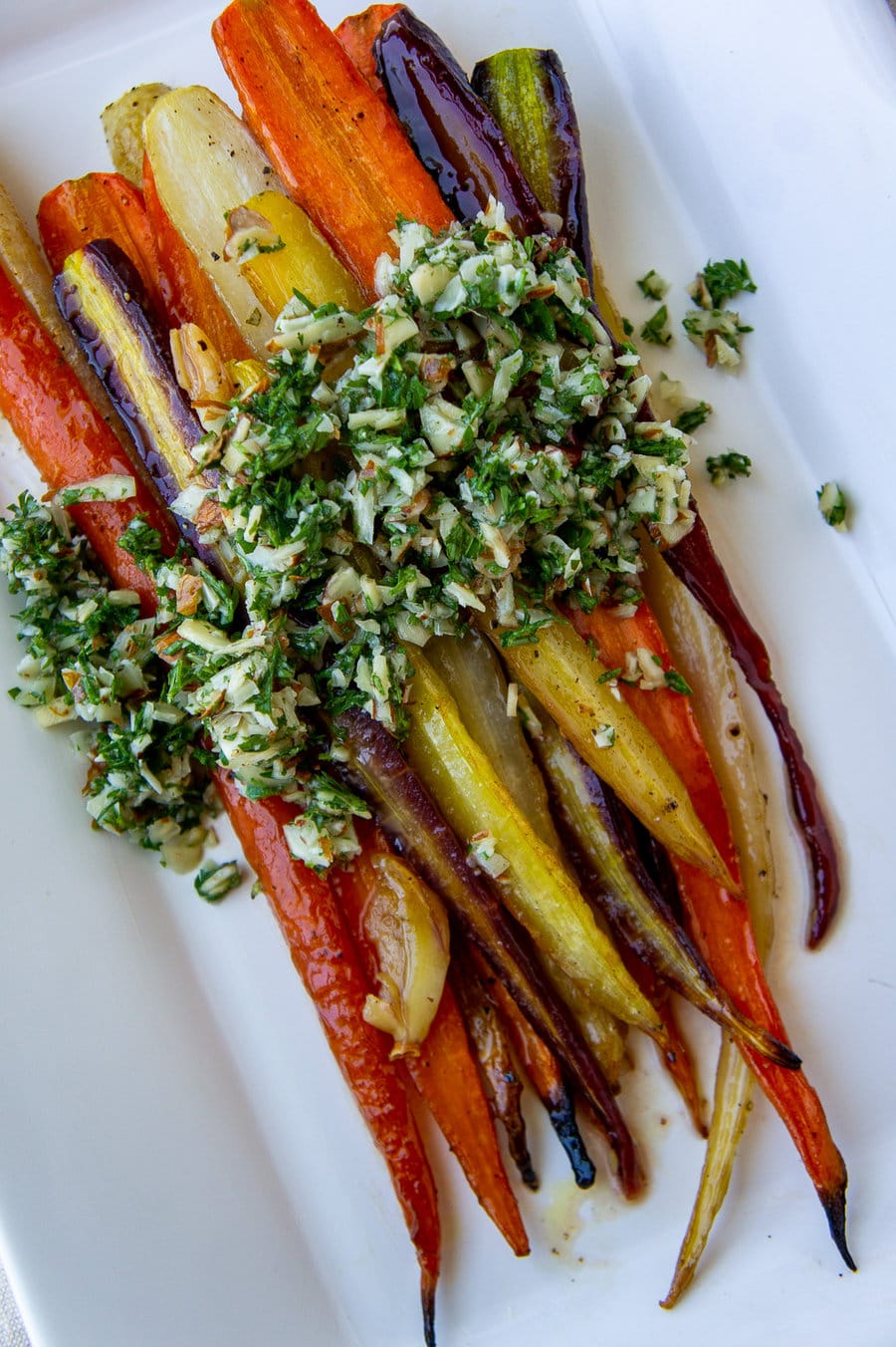 a platter of roasted glazed rainbow carrots topped with gremolata.