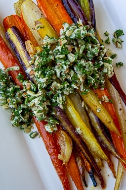 a platter of roasted glazed rainbow carrots topped with gremolata.