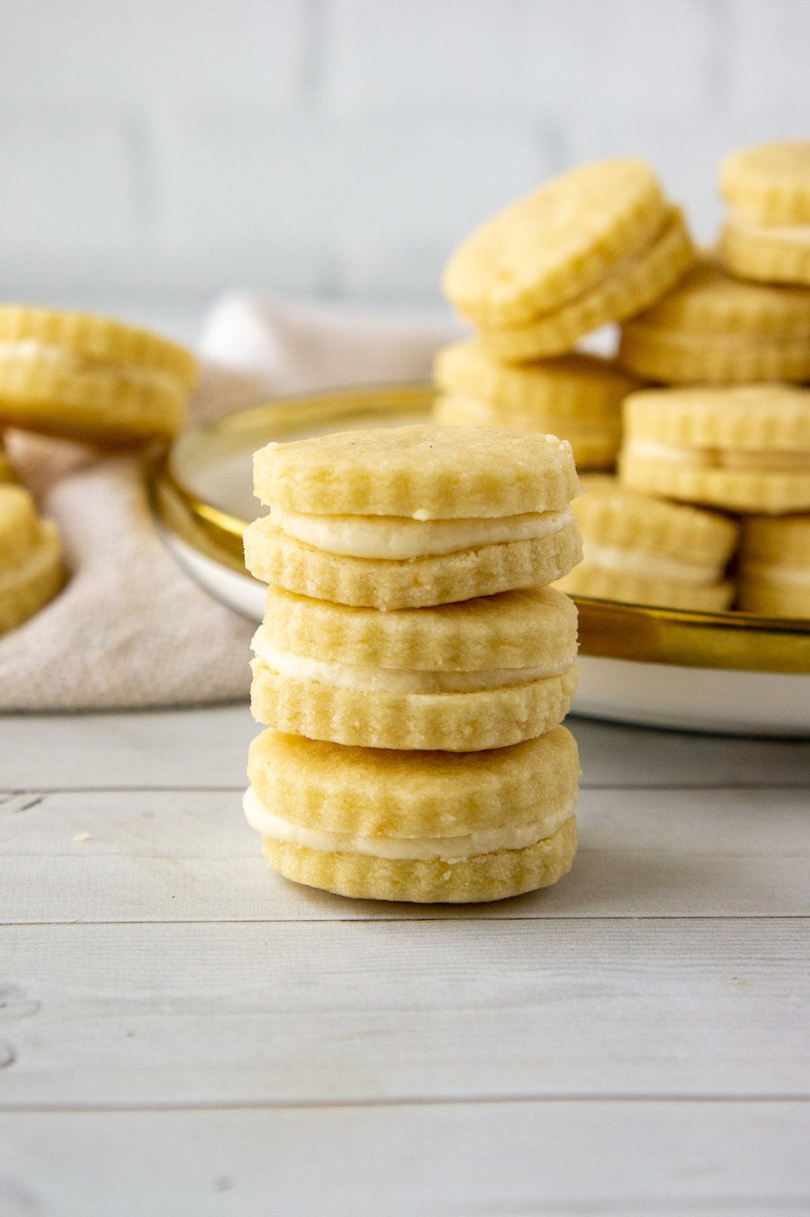a stack of maple sandwich cookies in front of a plate of more cookies.