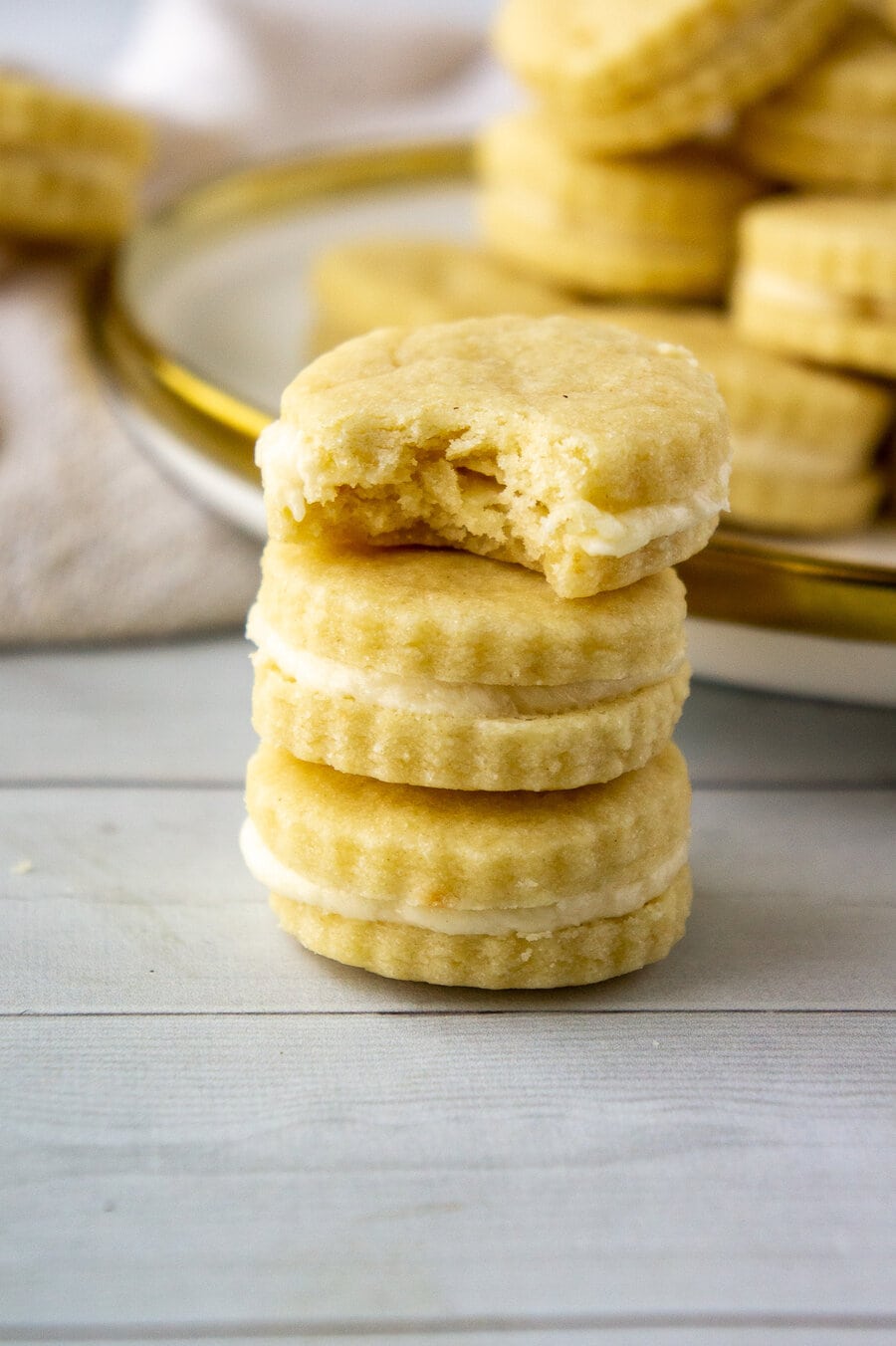 maple sandwich cookies stacked three high with the top missing a bite.