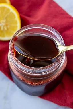 pomagranate molasses drizzling from a gold spoon into a jar.