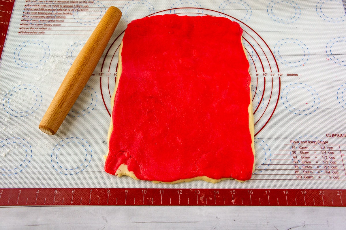 red and white sugar cookie dough layered on a baking mat.