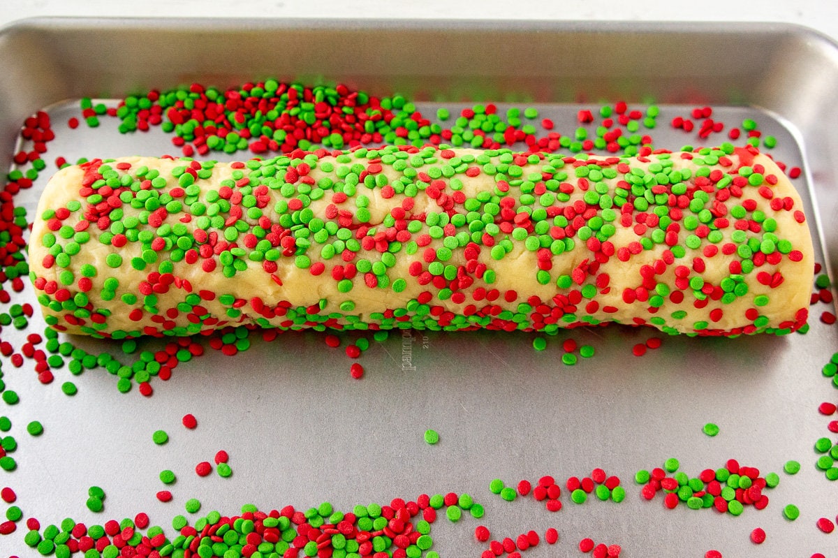 a pinwheel sugar cookie dough rolled in red and green sprinkles.