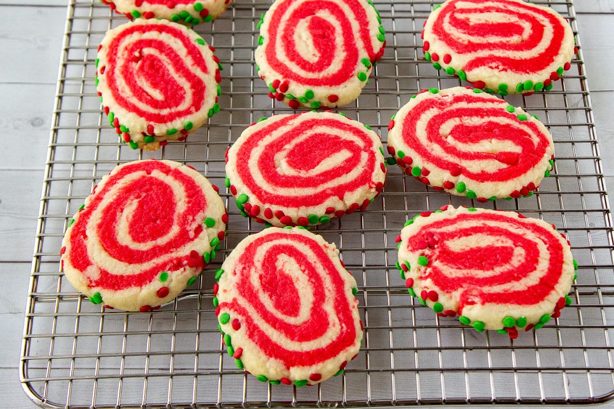 Christmas themed pinwheel cookies cooling on a baking rack.