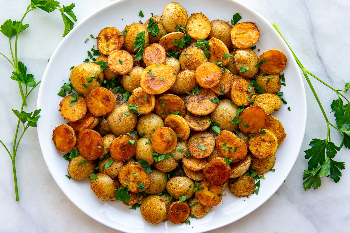 a white circular platter full of roasted baby potatoes.