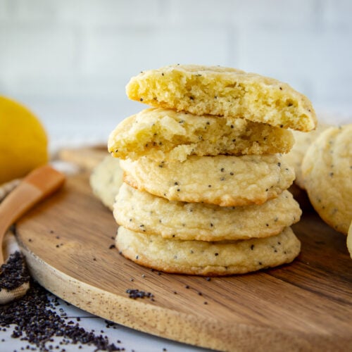 a stack of poppy seed cookies on a round wooden board.