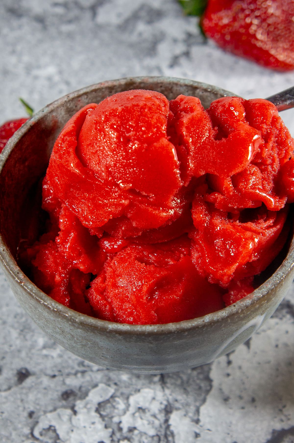 a bowl of strawberry sorbet scoops on a stone table.