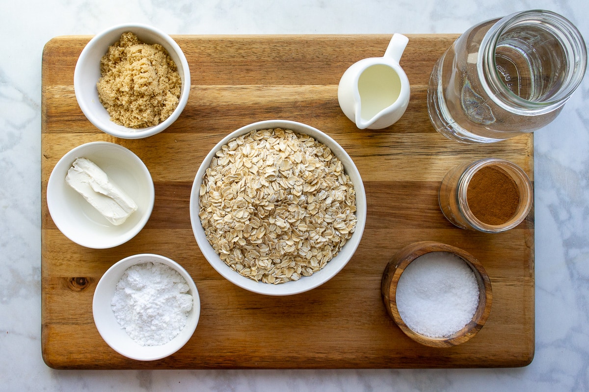 ingredients to make cinnamon roll flavored oatmeal including rolled oats, sugar, cream cheese, water, salt, and cream.