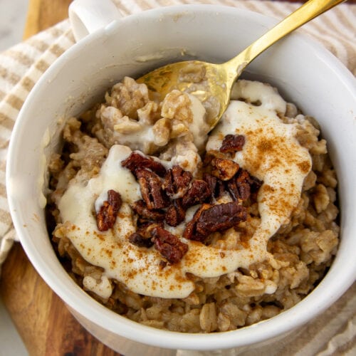 a bowl of oatmeal with a white icing and chopped nuts on top.