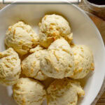 a bowl of drop biscuits with a cup of coffee beside it.