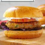 a turkey burger on a brioche bun with tomato, purple lettuce, and mayo on a cutting board.