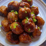 A plate of BBQ glazed turkey meatballs with chives on top.