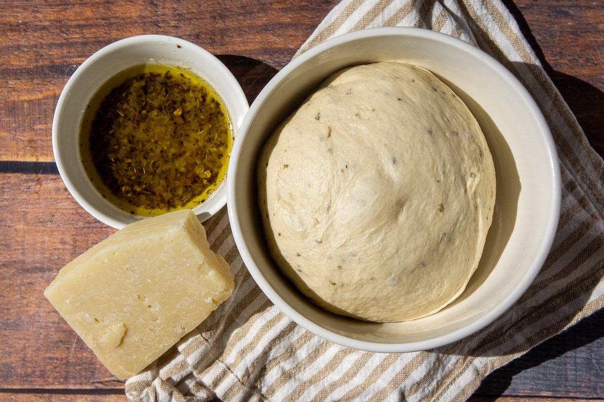 Ingredients needed to make garlic bread twists including pizza dough, garlic butter, and parmesan cheese.