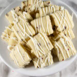 a stack of white chocolate drizzled raspberry shortbread cookies in a bowl.