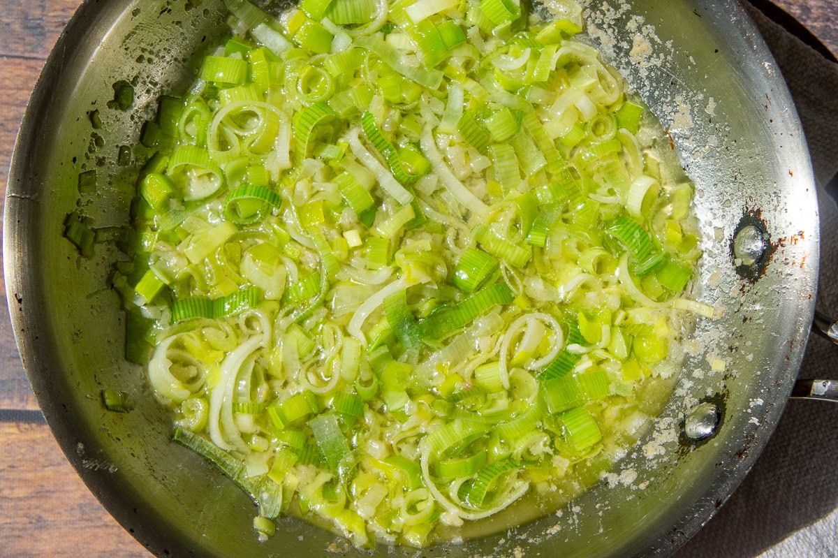 a saute pan with leeks simmering in butter.